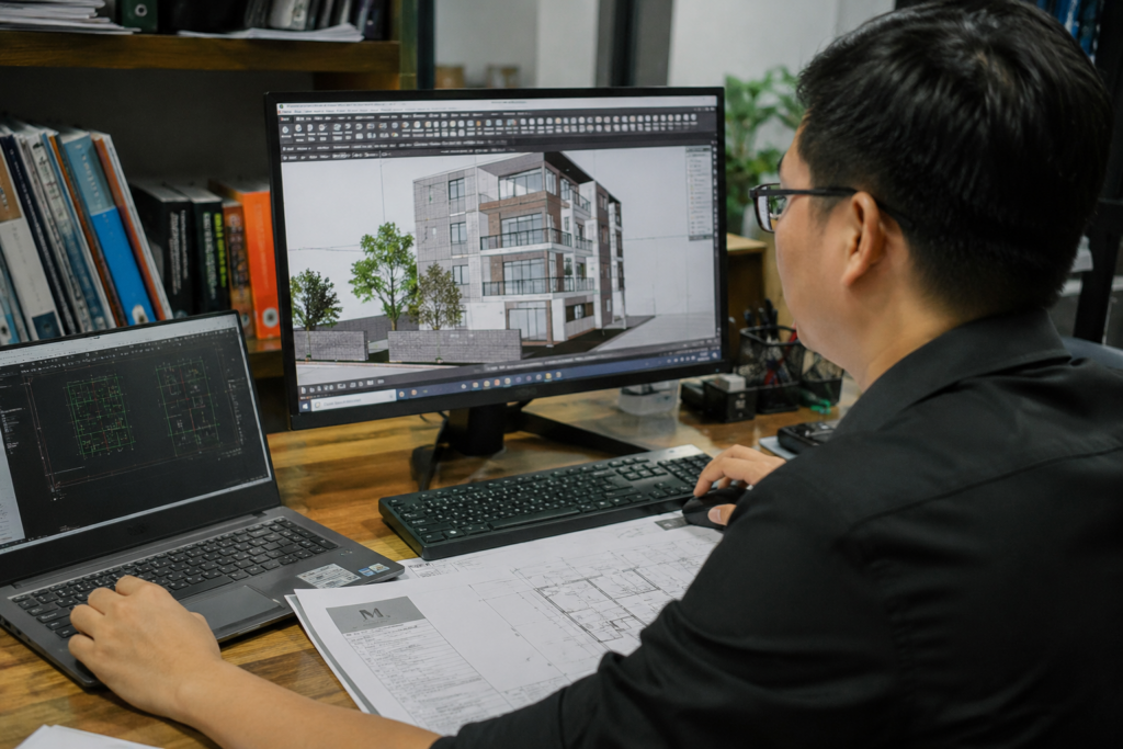 Kiến trúc sư đang làm việc với bản vẽ 3D và hồ sơ thiết kế nhà trên máy tính.