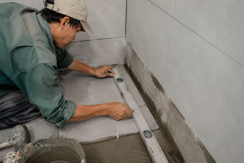 Công nhân đang thi công ốp lát gạch và kiểm tra độ phẳng bằng thước thủy trong quá trình hoàn thiện nhà.
